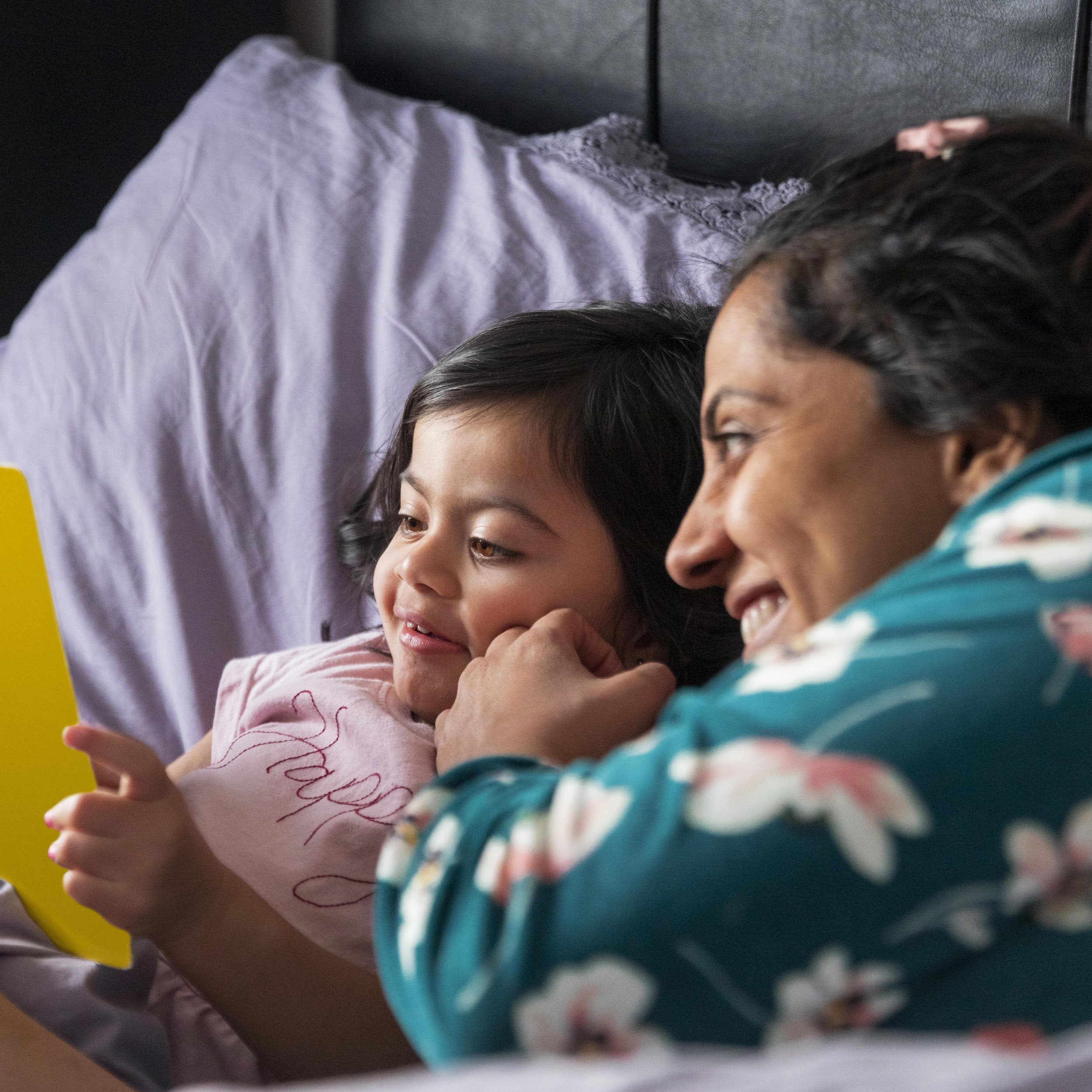 Mother and child reading a bedtime story together on child's bed