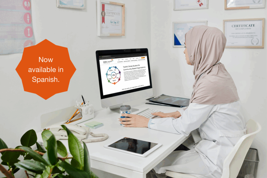Woman sitting at computer looking at Stress Busters CBO Toolkit
